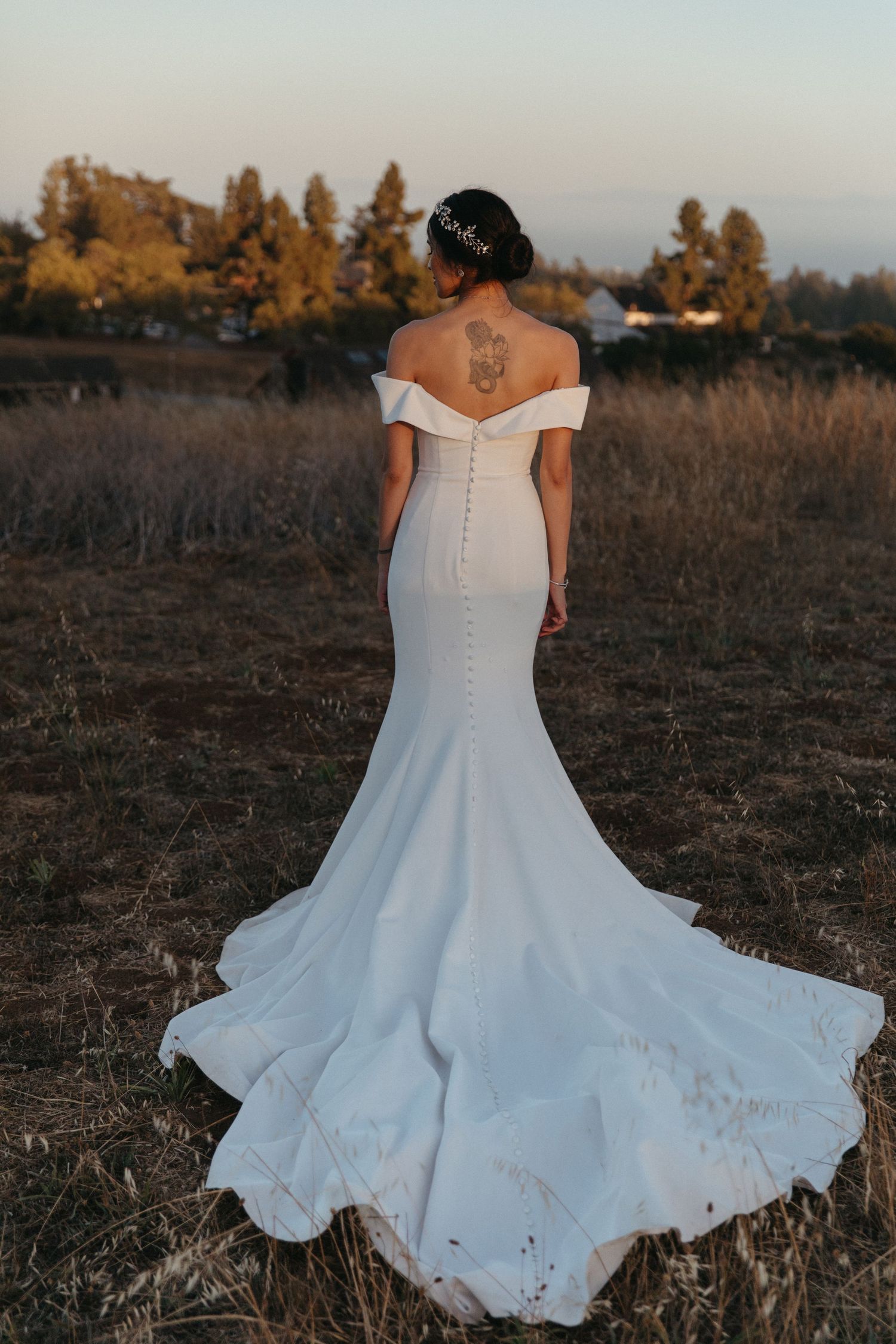 Back view of a mermaid wedding dress with dramatic train in a golden field.