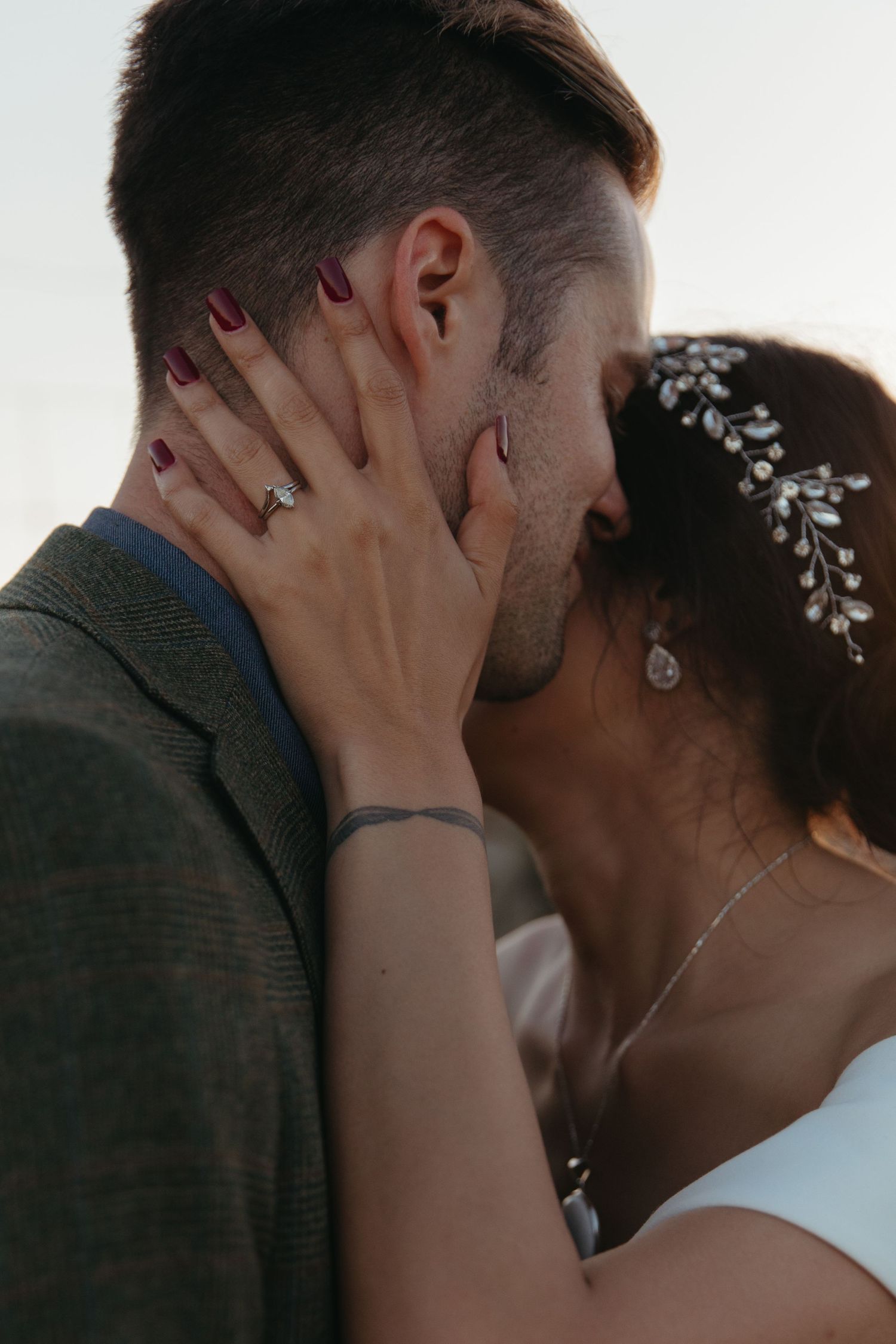 Intimate wedding moment captured in close-up showing jewelry and floral hair accessories.