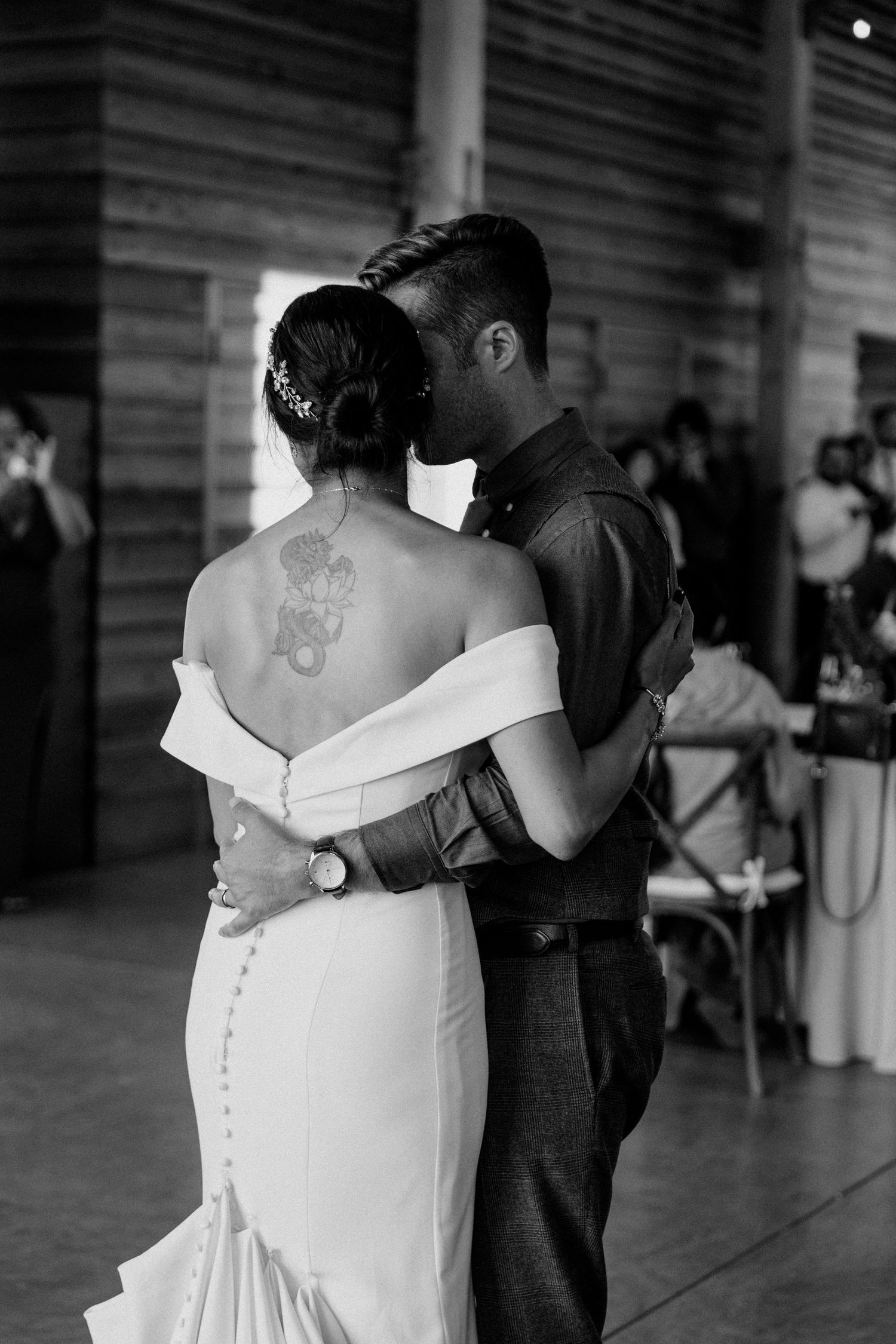 A couple shares an intimate dance moment showing the bride's back tattoo.