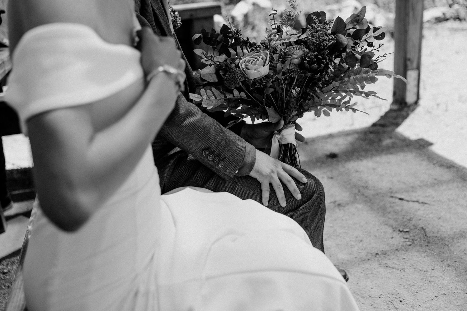 Black and white detail shot of wedding ceremony seating with flower bouquet arrangement.