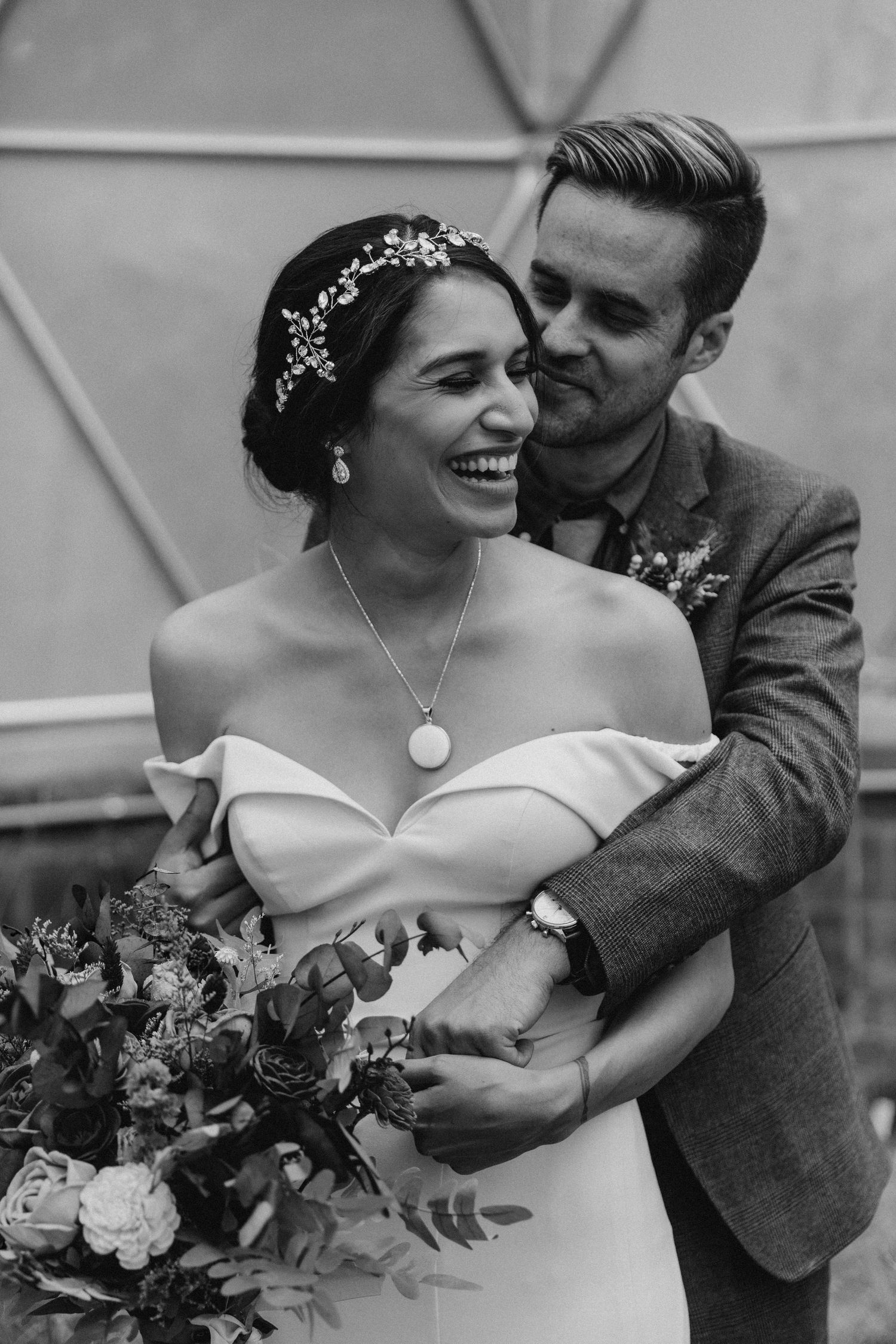A joyful moment captured in black and white with bridal bouquet and ornate headpiece.