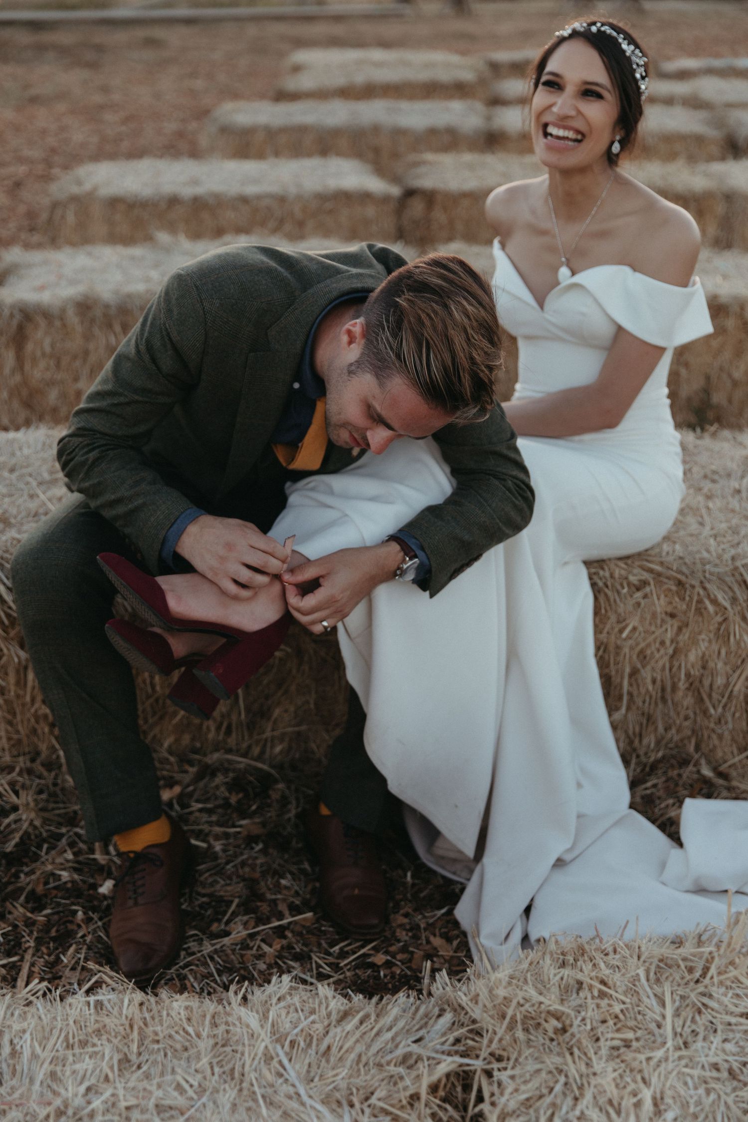 Candid wedding photo on terraced steps showing playful moment during shoe adjustment.