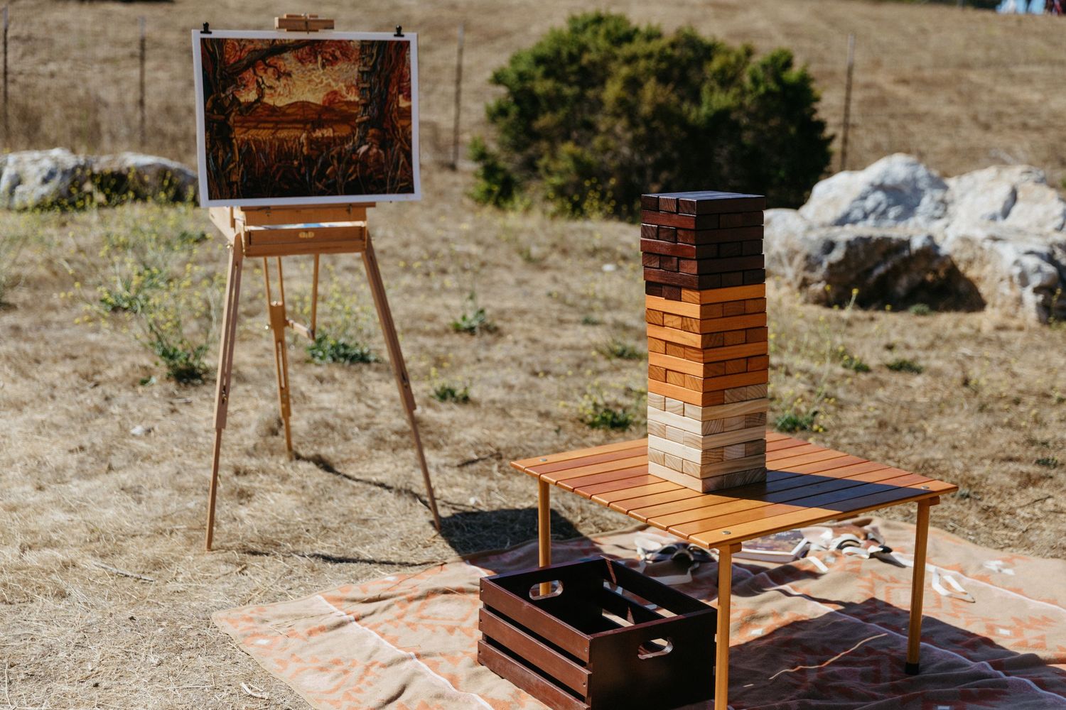 An outdoor art display setup with wooden easels and boxes in a desert landscape.