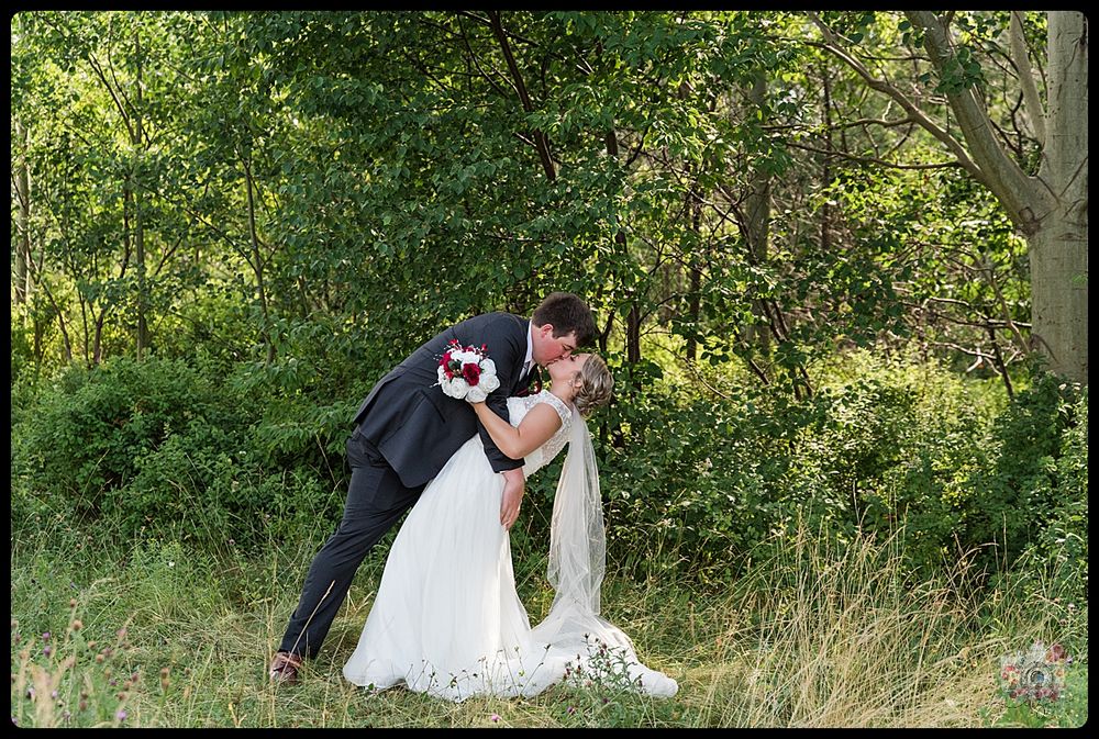 Romantic wedding photo of couple sharing intimate moment in natural outdoor setting.