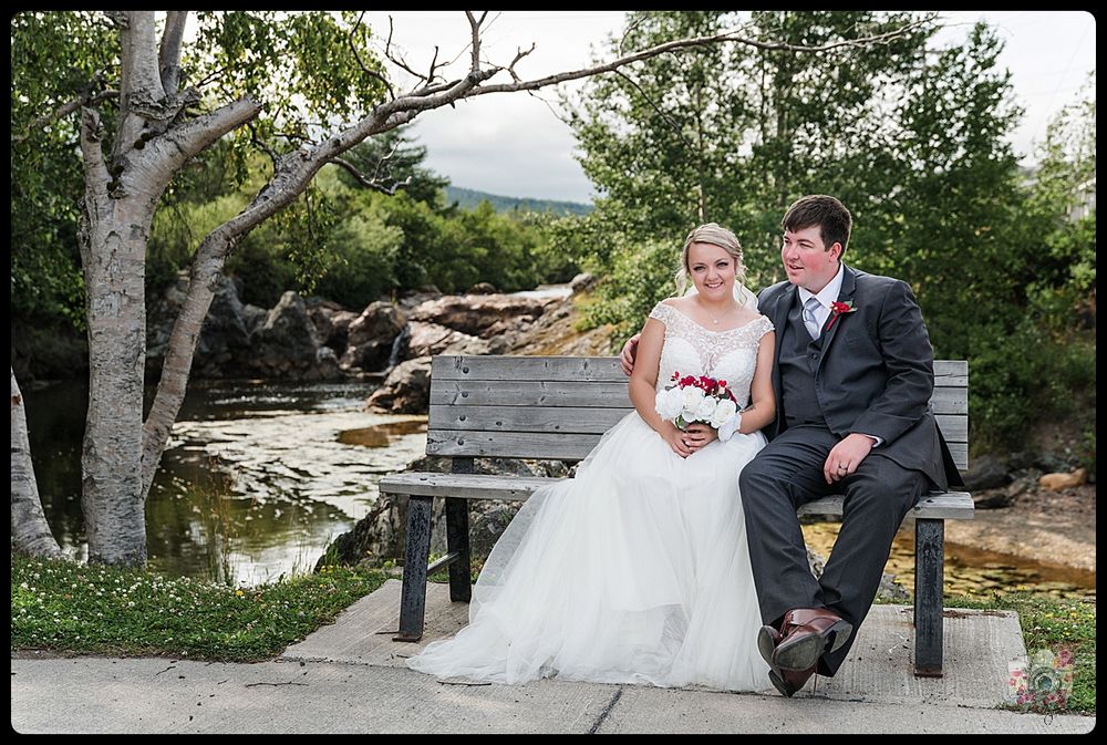 Couple sits on bench overlooking rocky waterfall landscape.