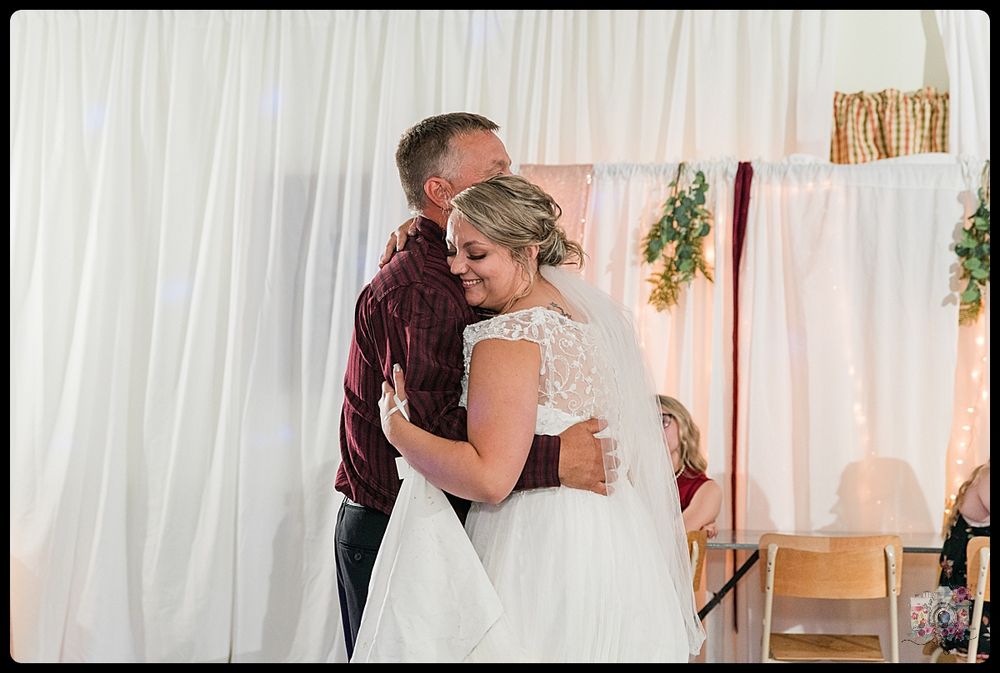 Intimate wedding dance captured against white curtained backdrop with romantic lighting.