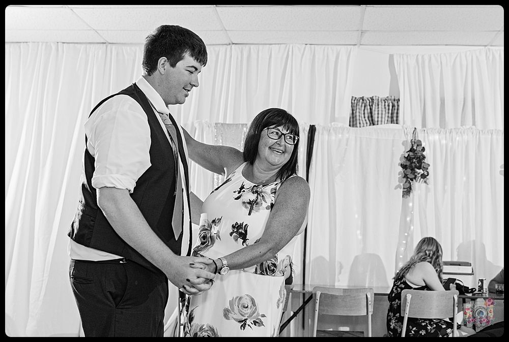 Wedding reception couple dancing and laughing together in front of white curtained backdrop.