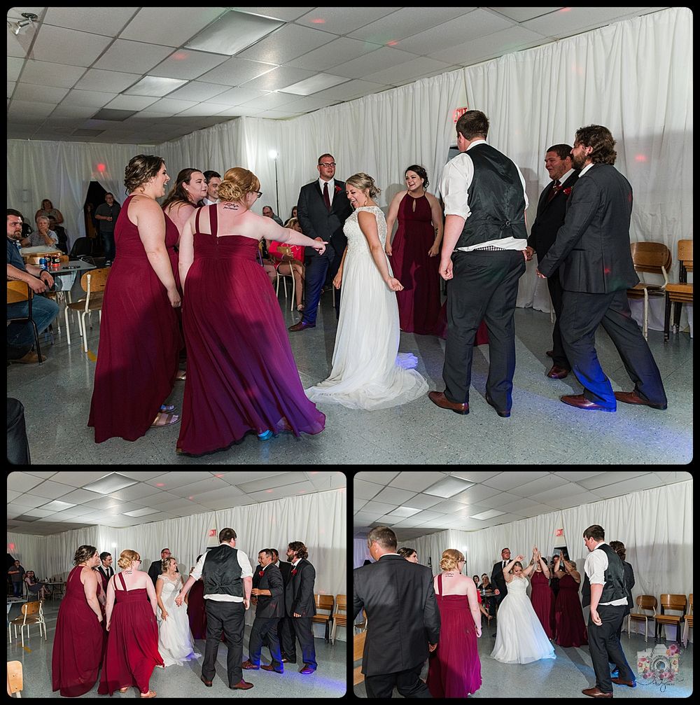 Wedding party in burgundy dresses celebrating on dance floor with bride and other guests.