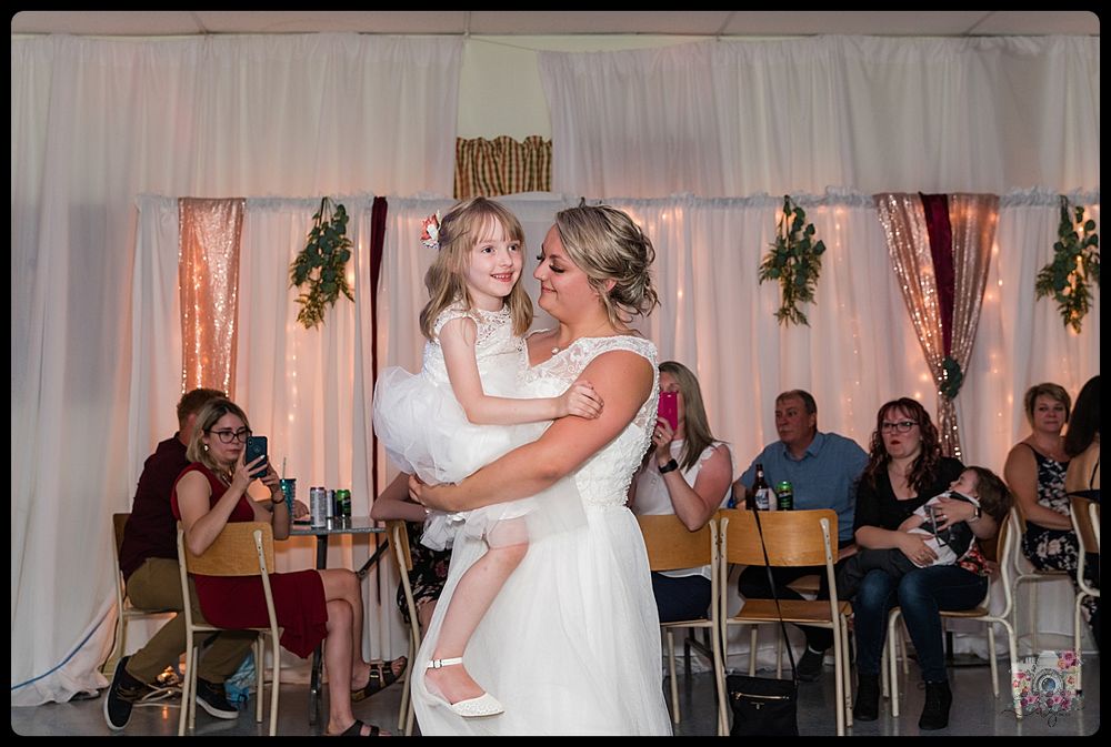 Joyful celebration during wedding reception with guests watching in background.