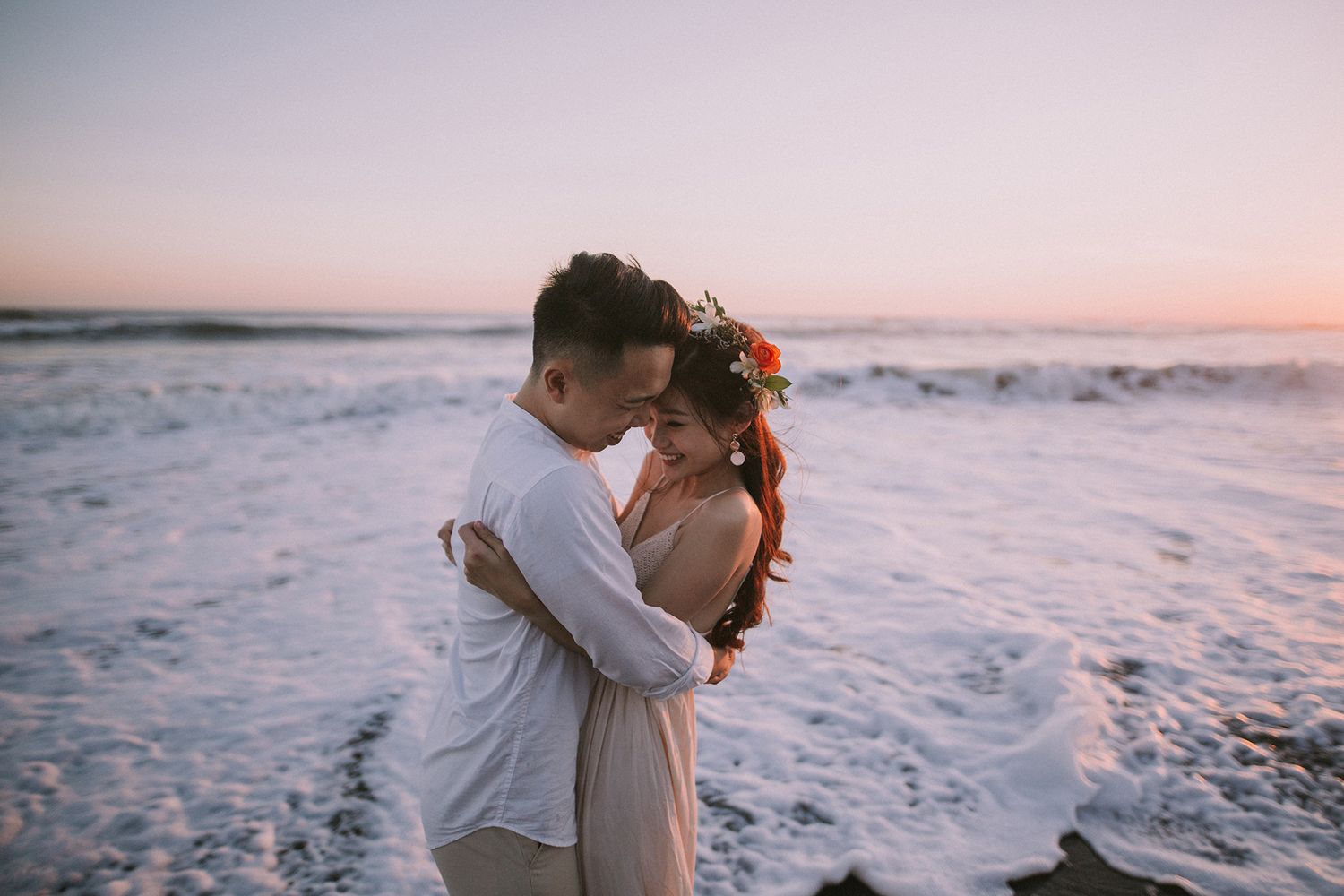 Intimate moment captured on beach during sunset with ocean waves.