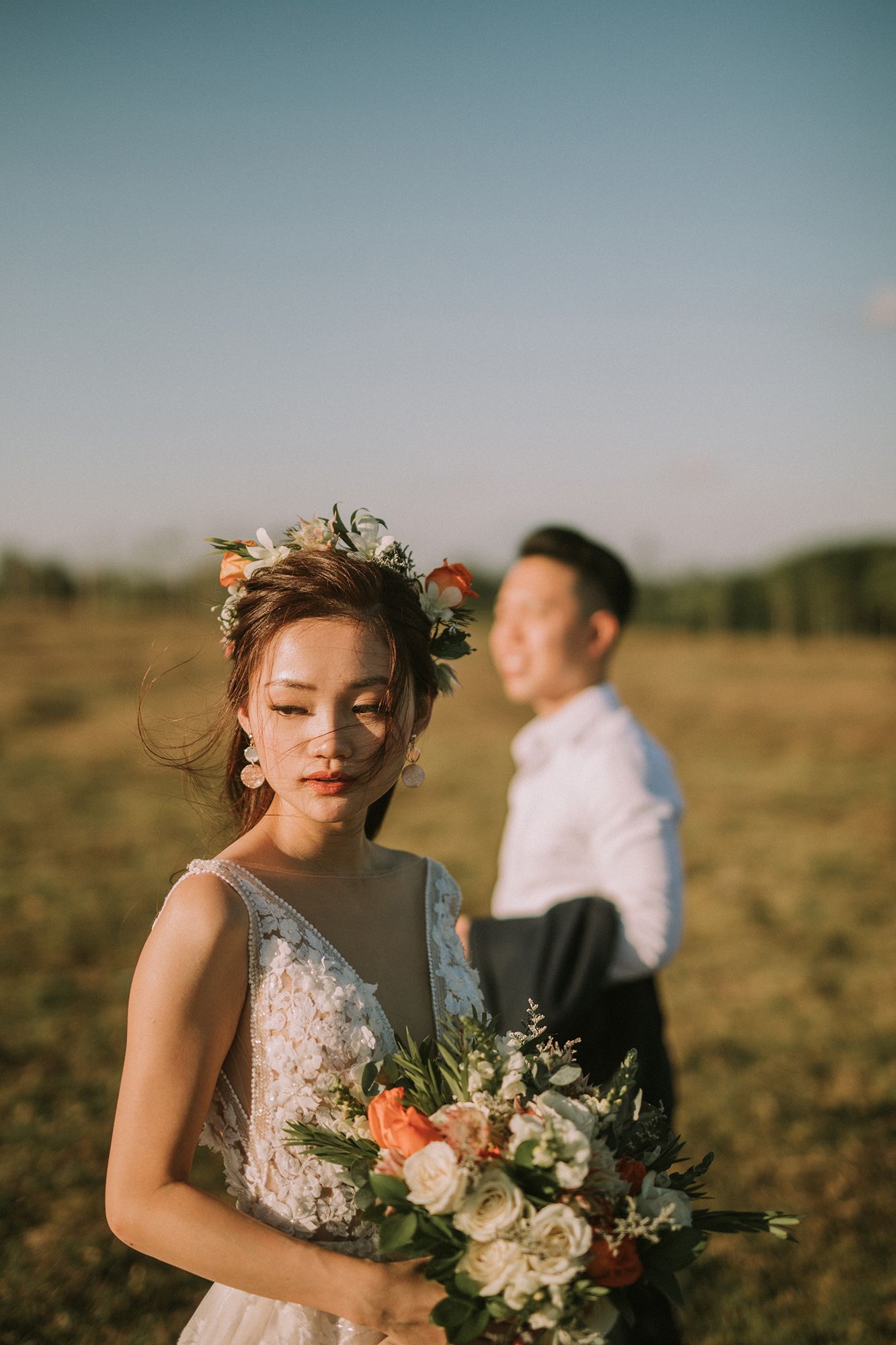 A romantic sunset wedding photoshoot in a golden field with a delicate lace dress and floral bouquet.