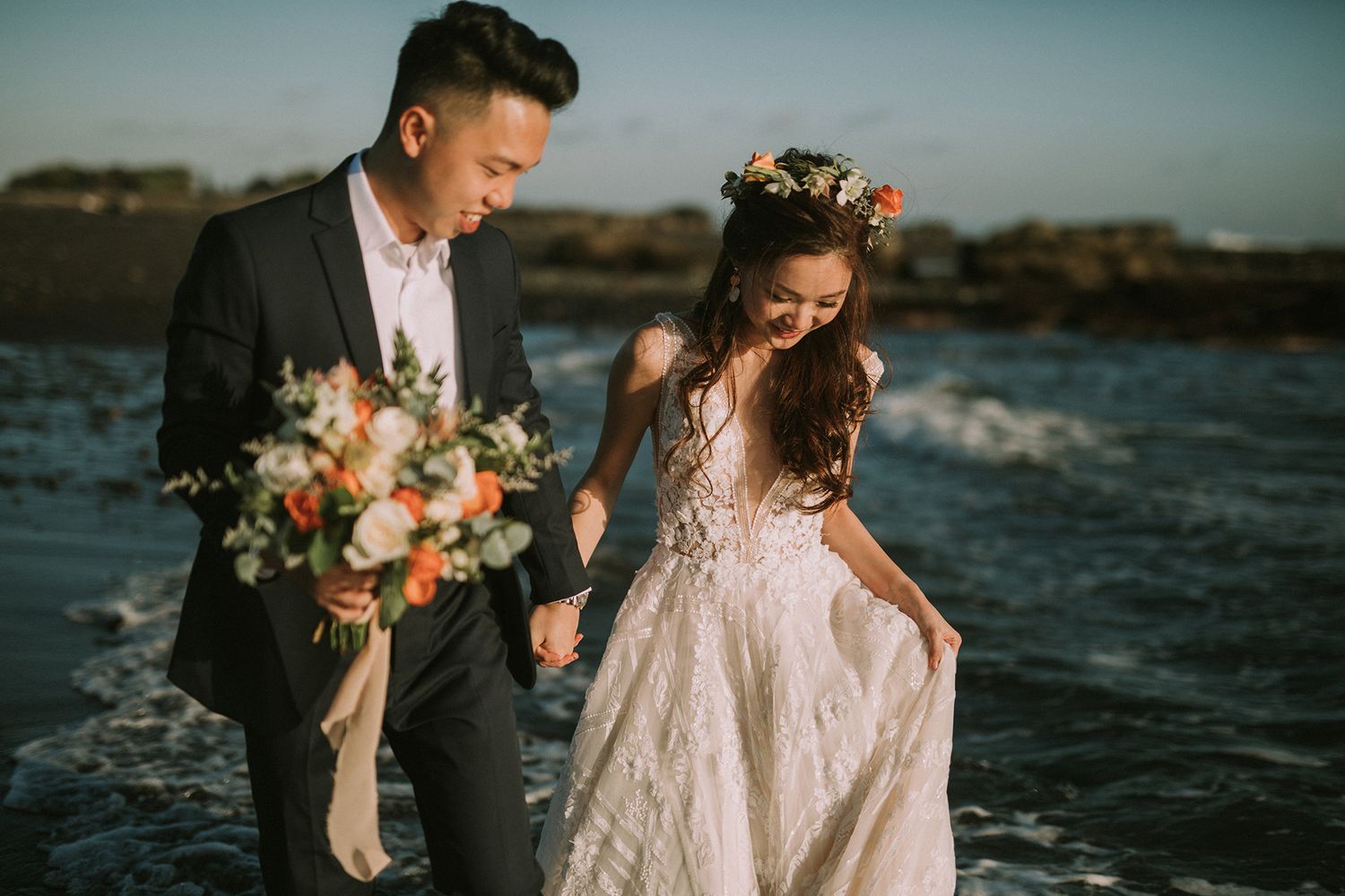 A coastal wedding photography session with dramatic rocky shoreline and ocean waves.