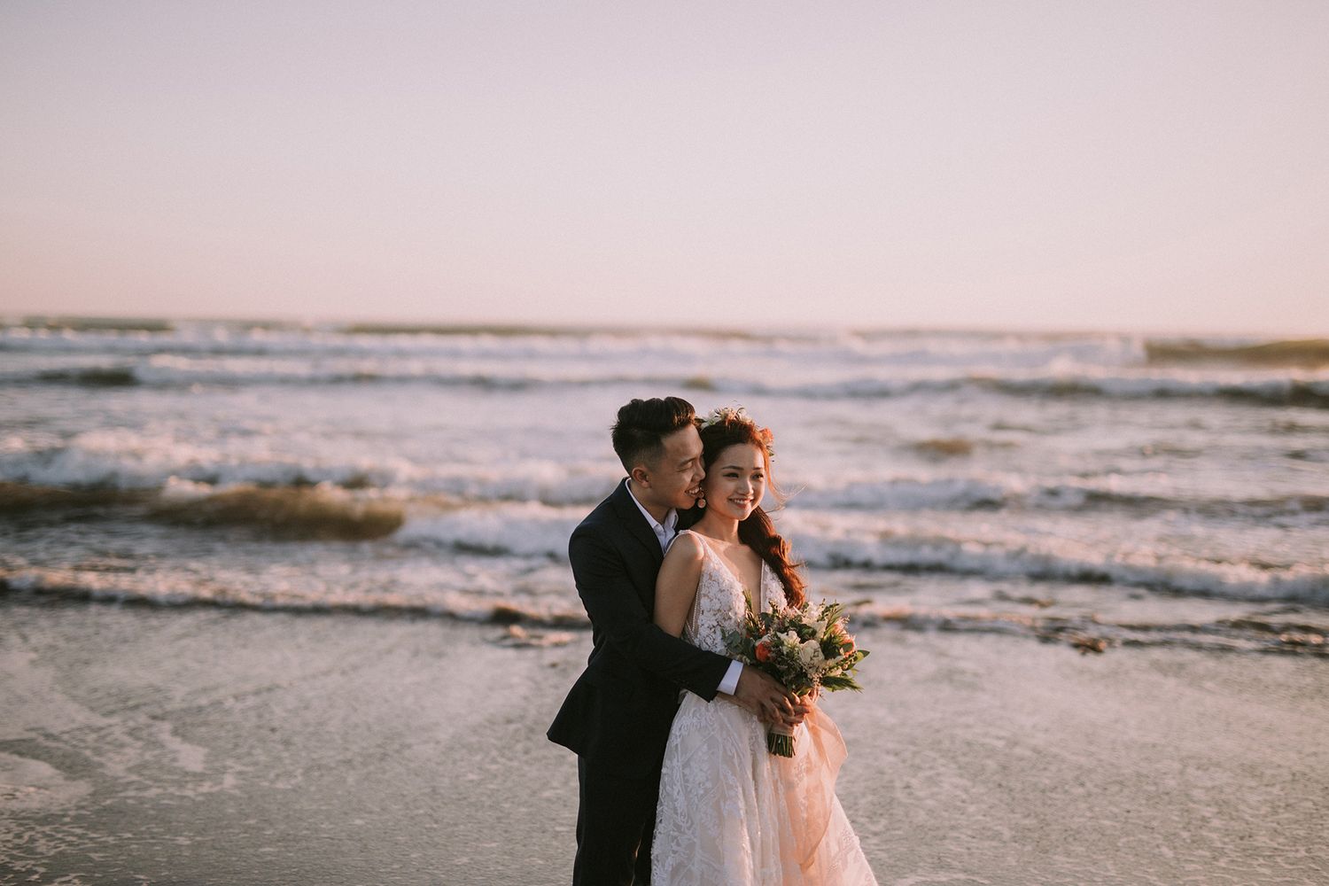 Romantic beach wedding portraits with waves and golden sunset light.