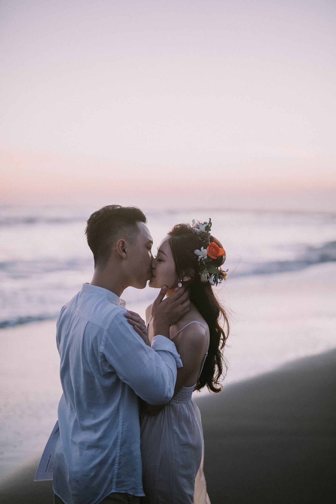 Romantic sunset beach portrait with waves crashing in background.
