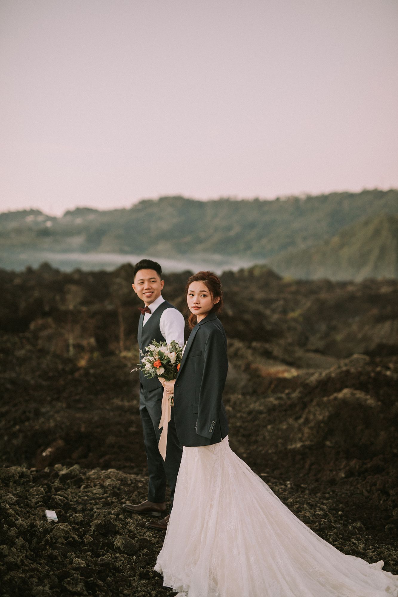 Wedding couple embraces on dramatic volcanic landscape at sunset.