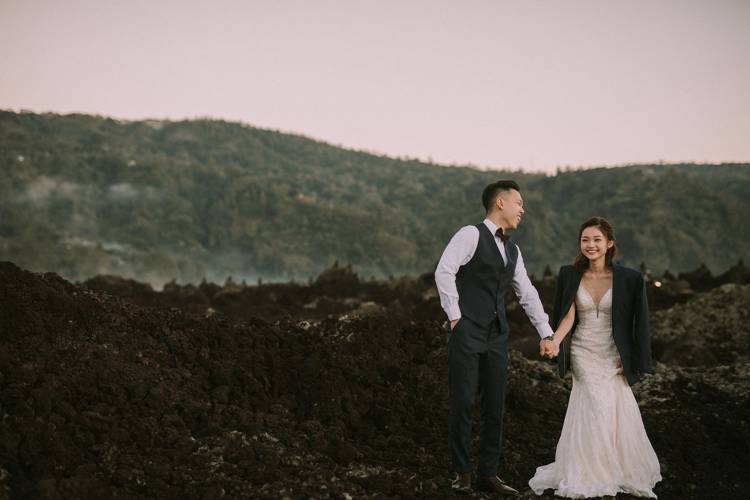 Wedding photography session on volcanic terrain with mountains in background.