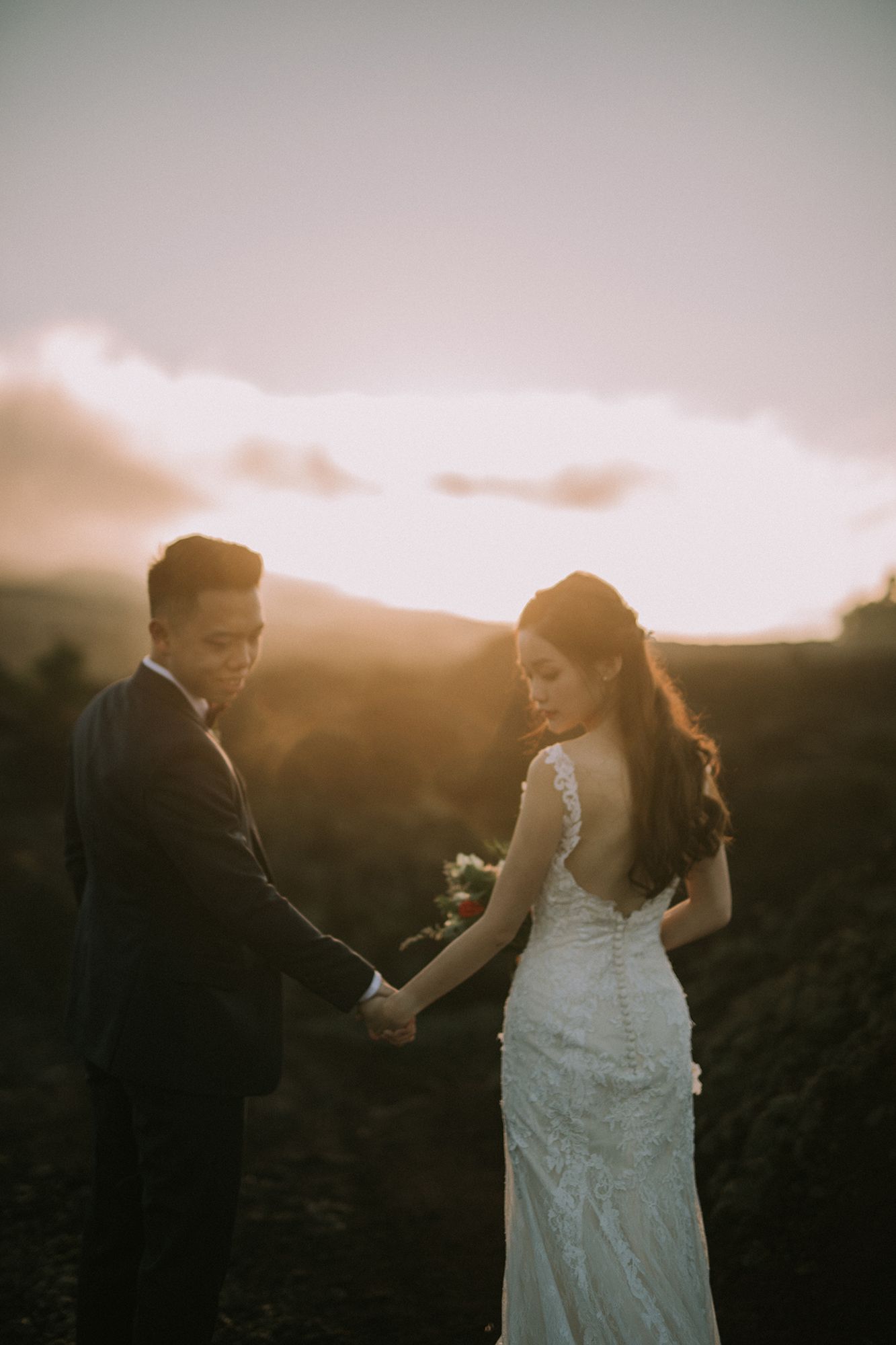 Silhouetted wedding couple dances at sunset with mountains in background.