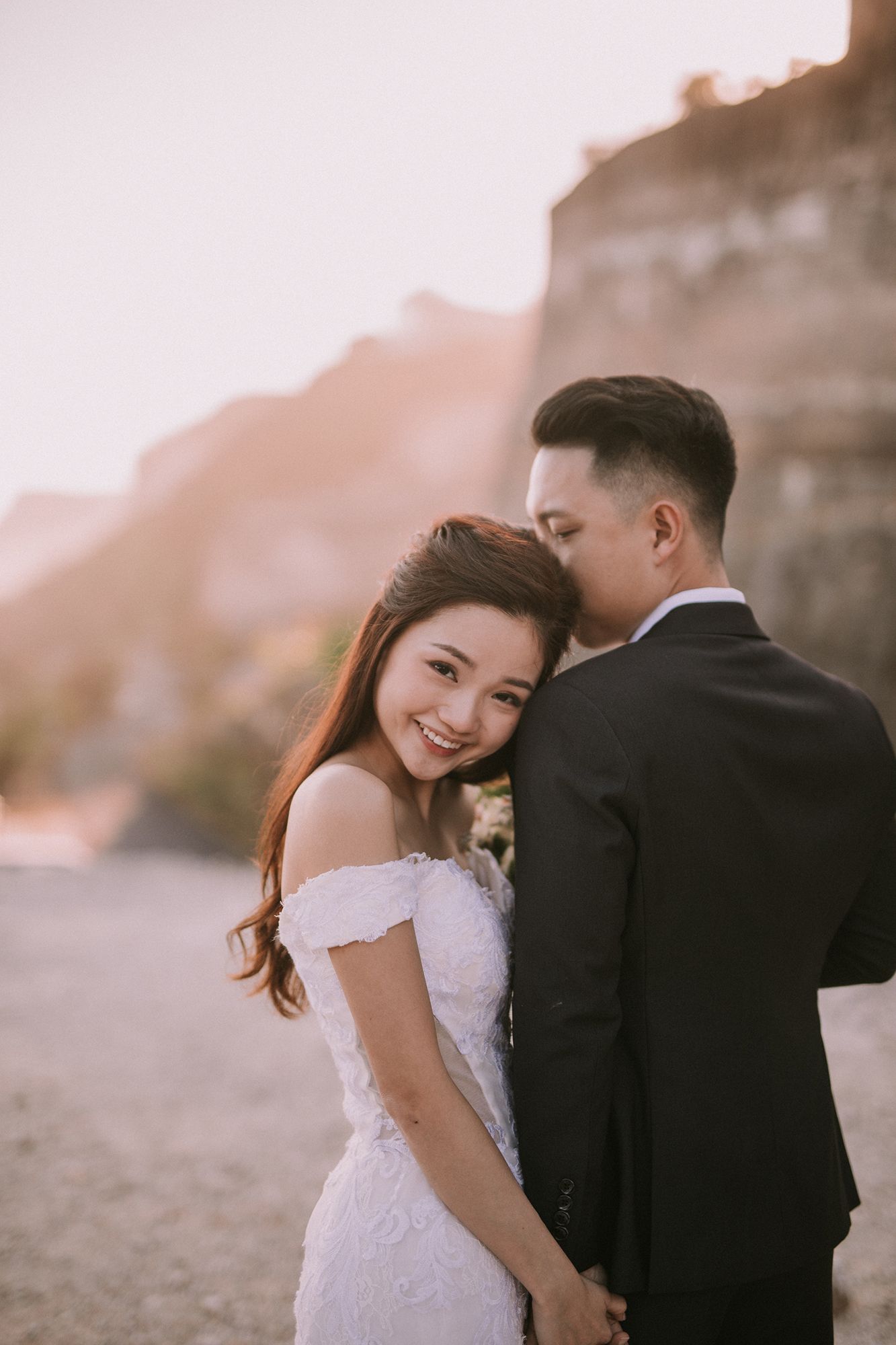Candid wedding moments captured against rocky cliffside at sunset.