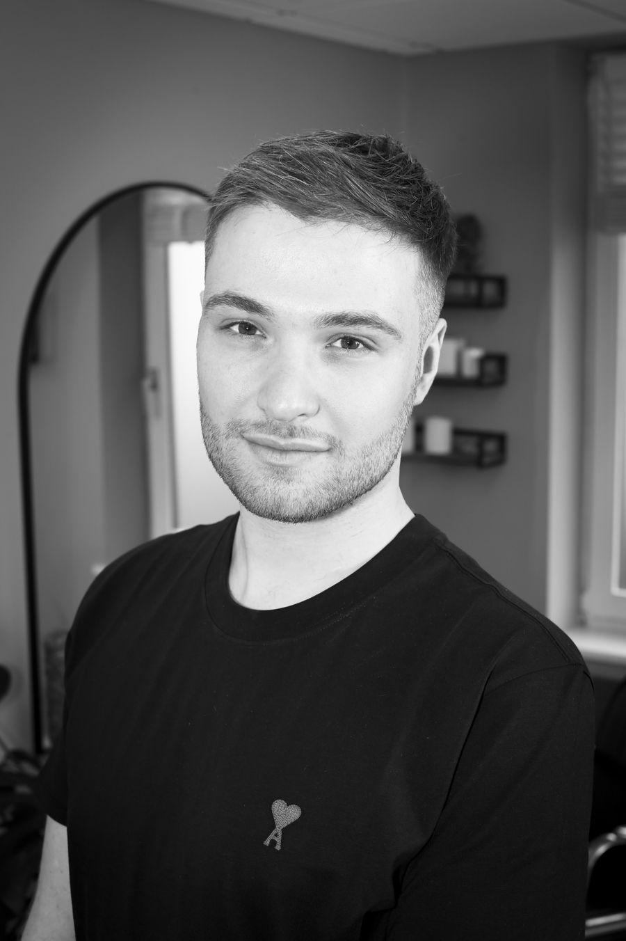 Joe Price, a hairstylist, poses in a black t-shirt before a mirror during a professional branding photoshoot by Abigail's Studio