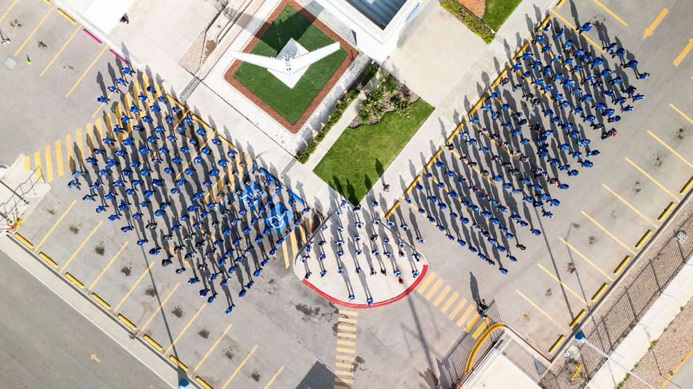 Aerial view of students forming the letters 'UCLA' on a campus lawn during a school spirit event.
