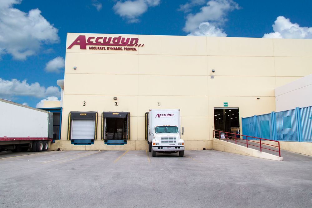 Loading dock at Accurun warehouse facility with white delivery truck parked at bay under blue sky.