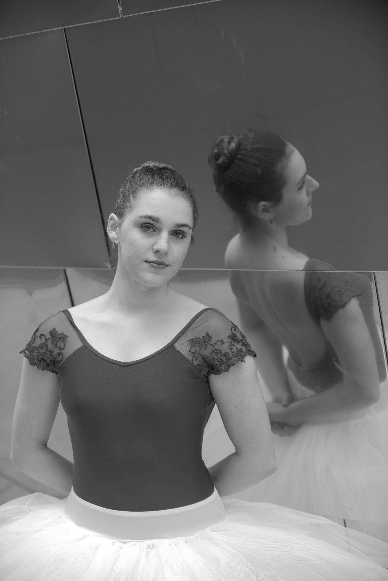 Ballet dancer in tutu and lace-detailed leotard poses in artistic black and white portrait.