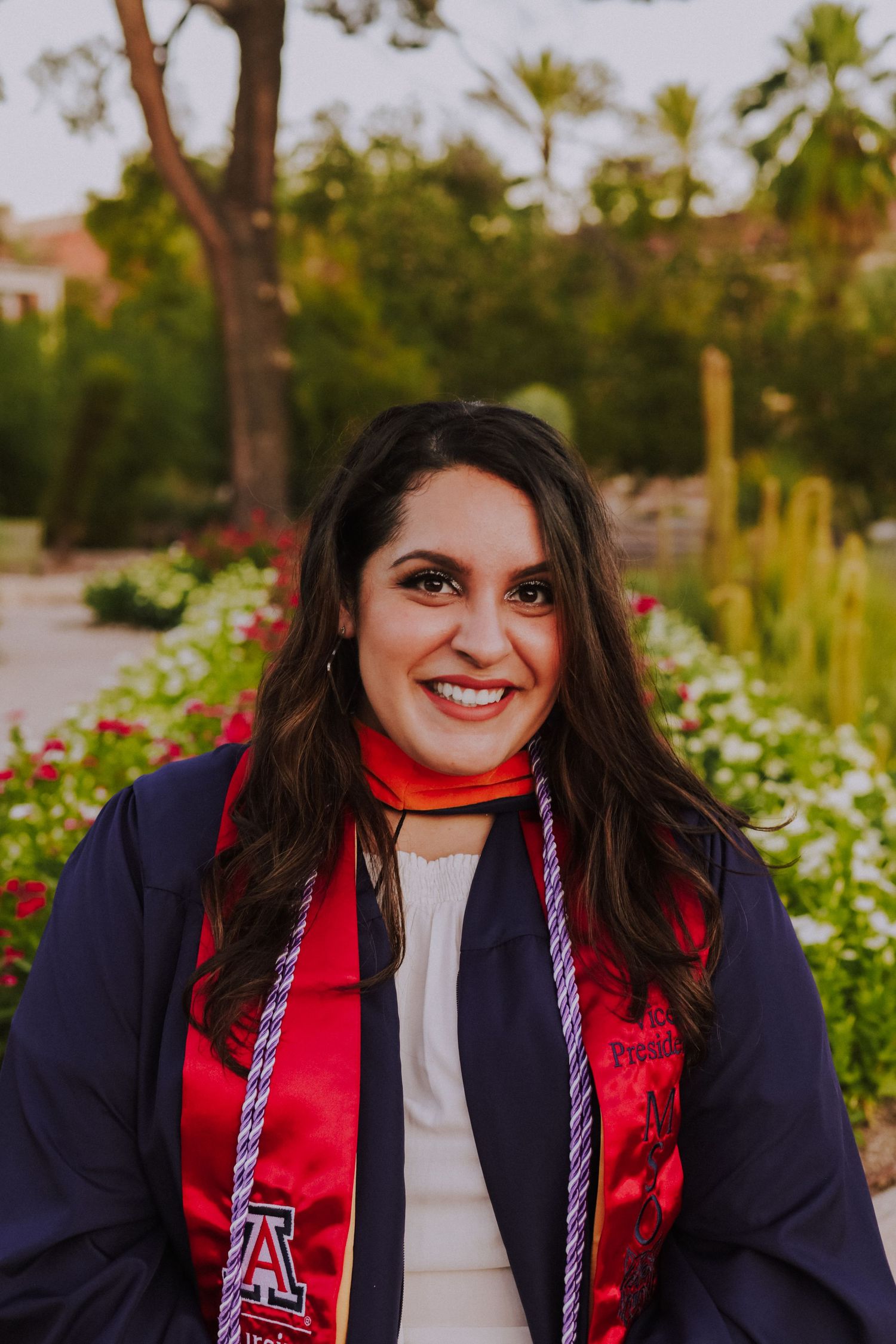 A graduation portrait featuring someone in academic regalia with University of Arizona stole and navy gown.
