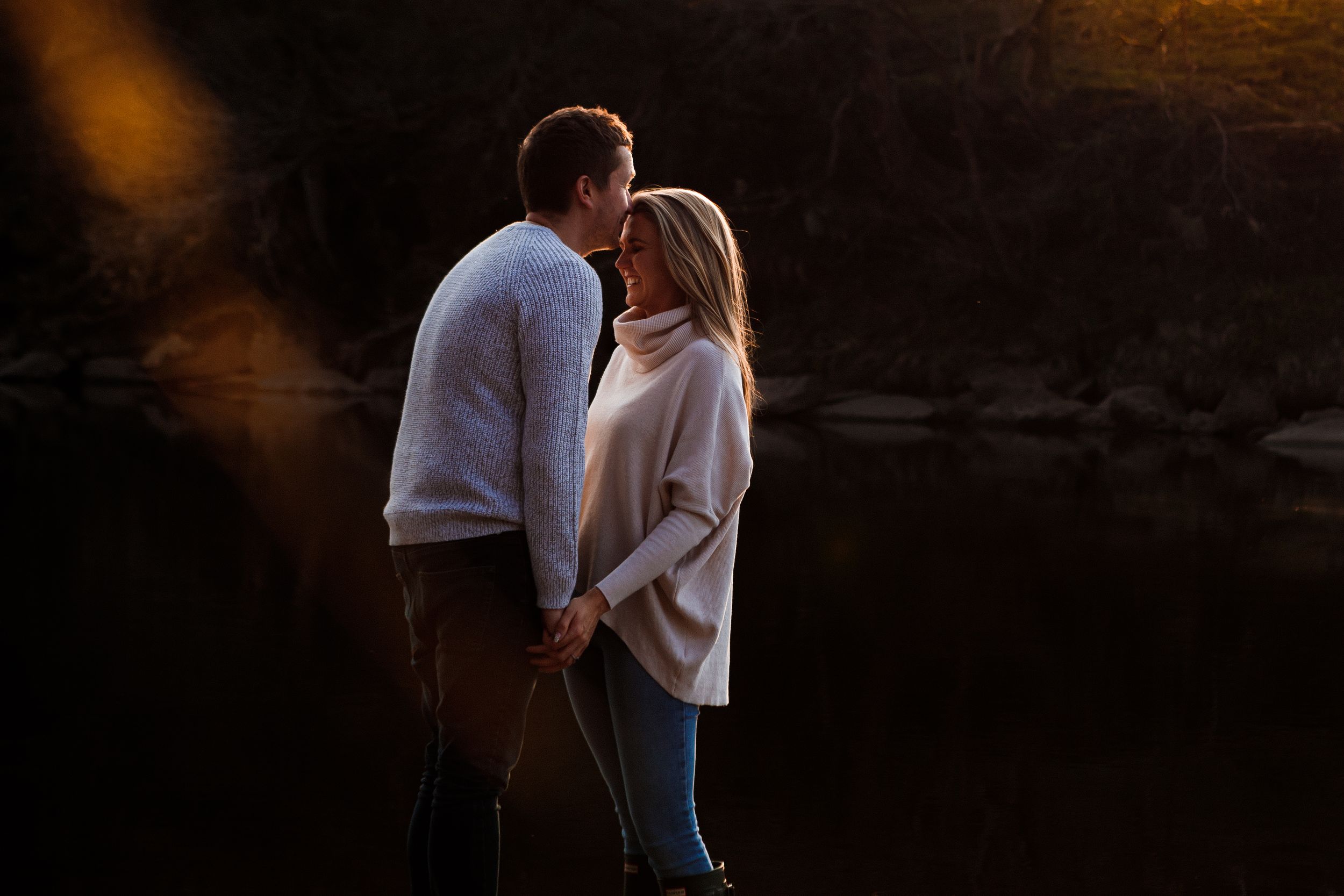 "couple engaged kissing by river"