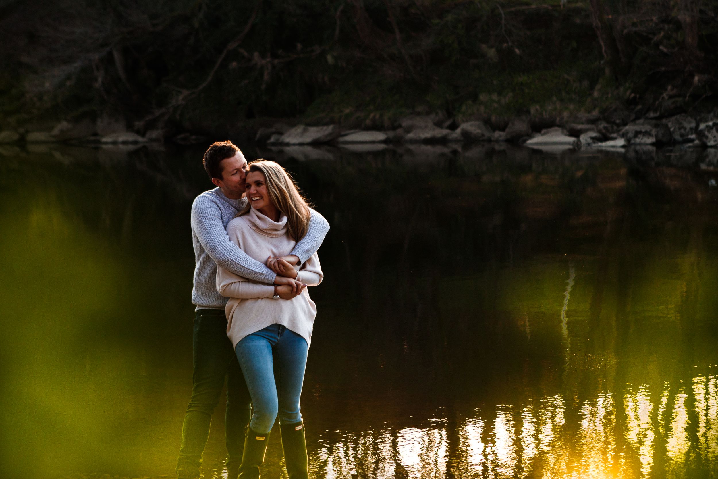"couple laughing hugging by river"