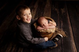 Moody lifestyle portraits of children on dark wooden floors with dramatic lighting.