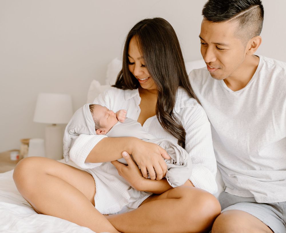 A family photoshoot by Moments With Kell on Oahu in Hawaii with new parents looking at their new baby