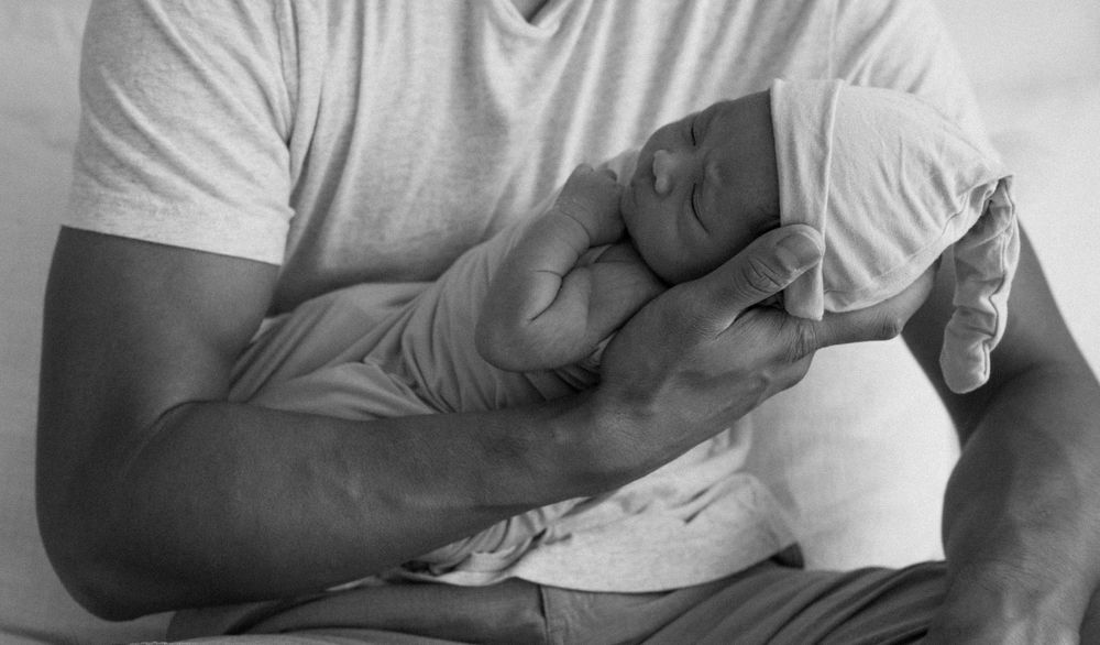 A family photoshoot by Moments With Kell on Oahu in Hawaii with new father looking at his new baby