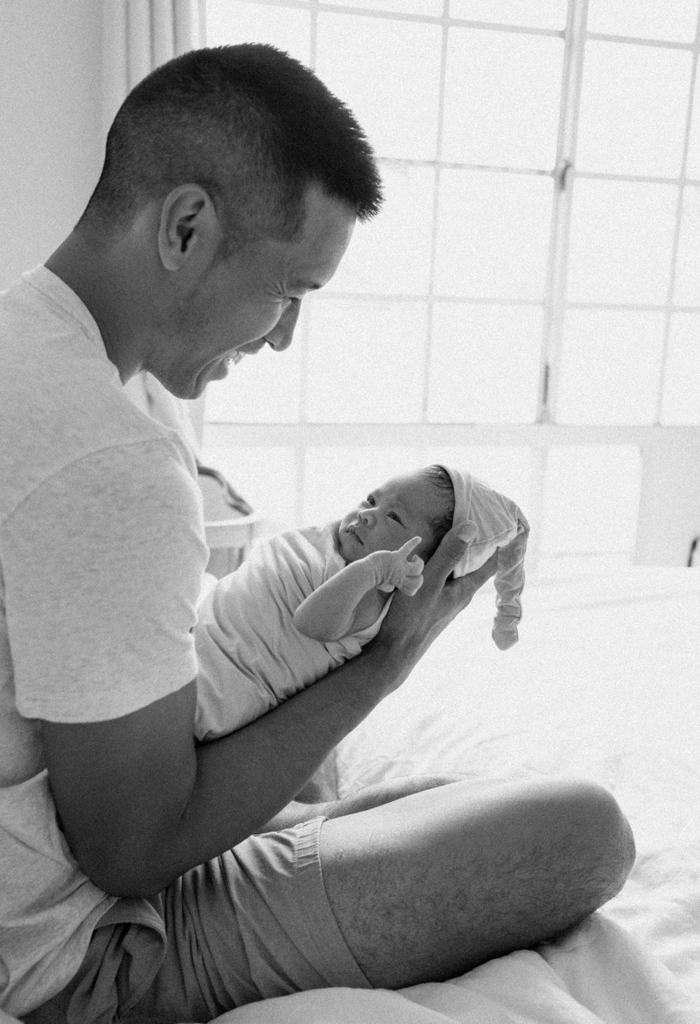 A family photoshoot by Moments With Kell on Oahu in Hawaii with new father looking at his new baby