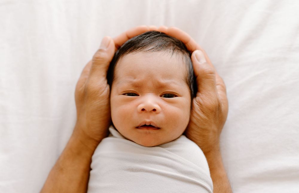 A family photoshoot by Moments With Kell on Oahu in Hawaii with parent holding their new baby