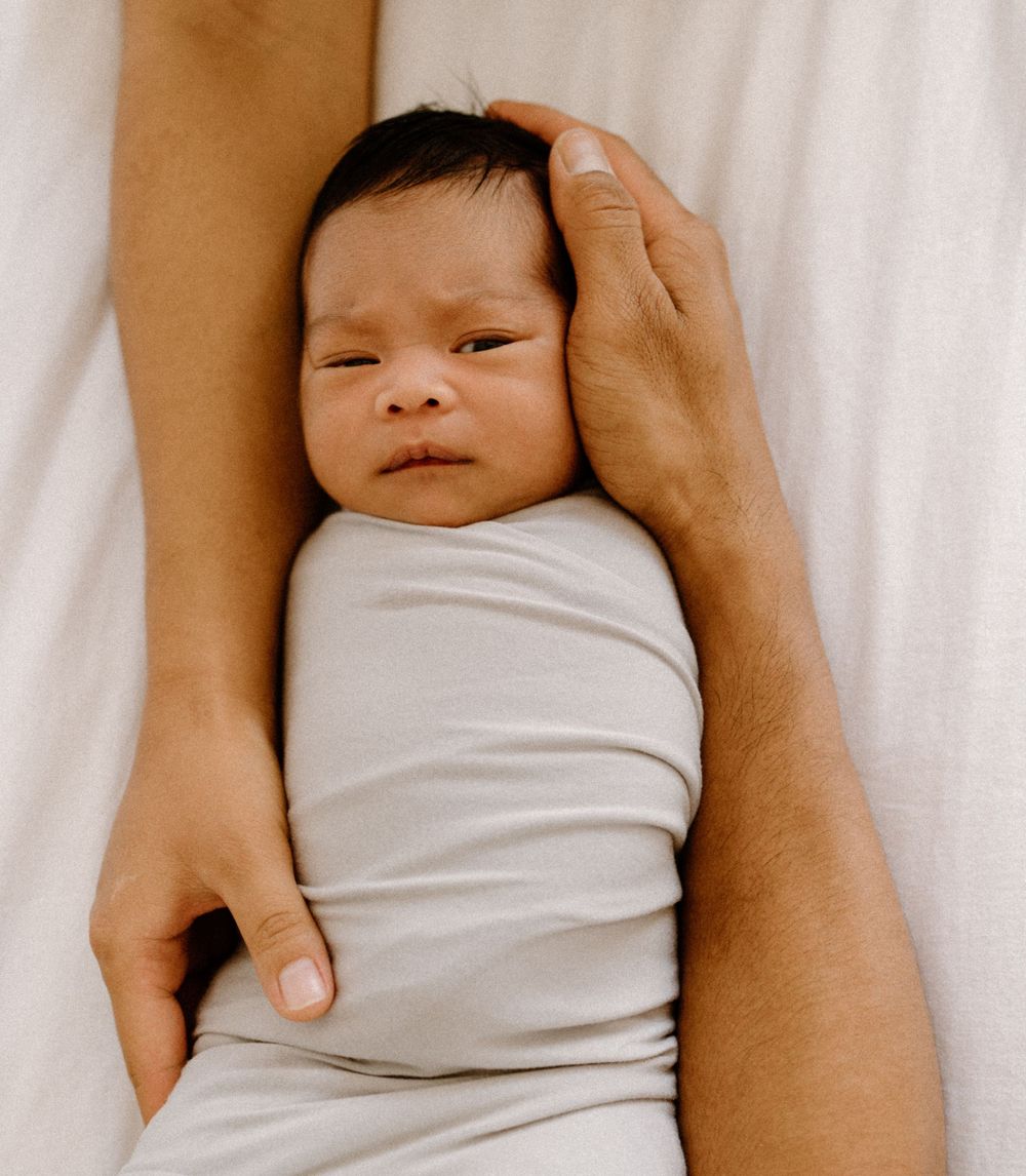 A family photoshoot by Moments With Kell on Oahu in Hawaii with parents holding their new baby