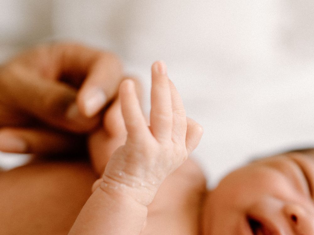 A family photoshoot by Moments With Kell on Oahu in Hawaii with new baby wrinkled hand