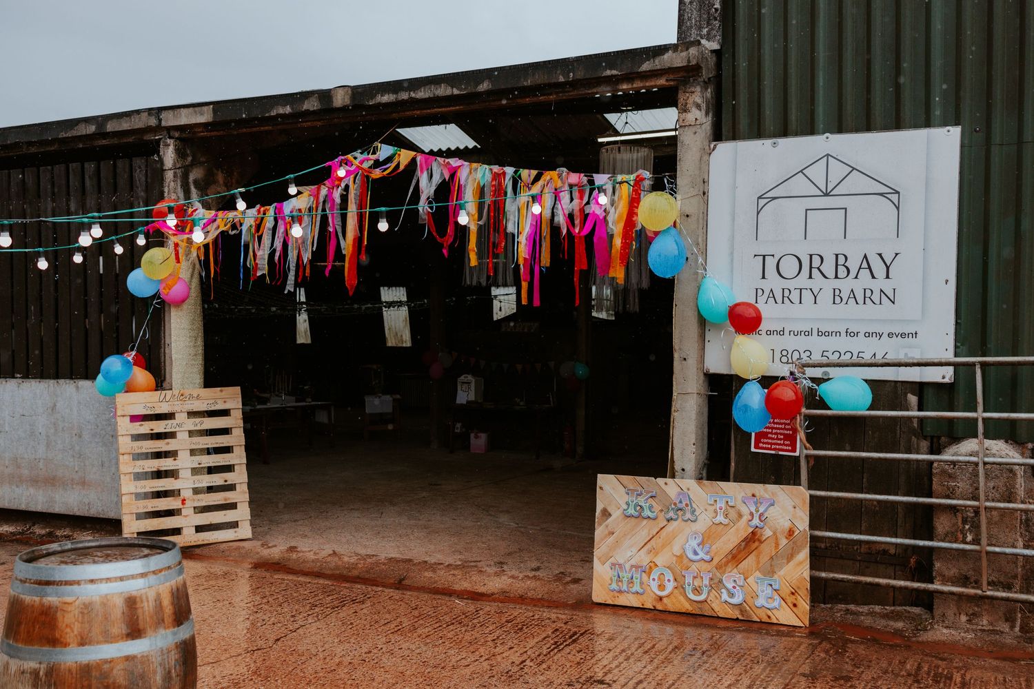 Colorful decorations and banners outside the Torbay Arts Barn rustic venue.