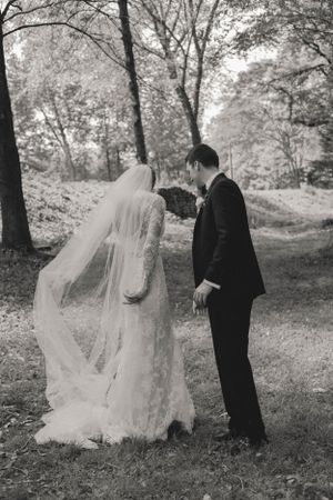 Black and white photo of bride and groom sharing an intimate moment in a lush outdoor park setting.