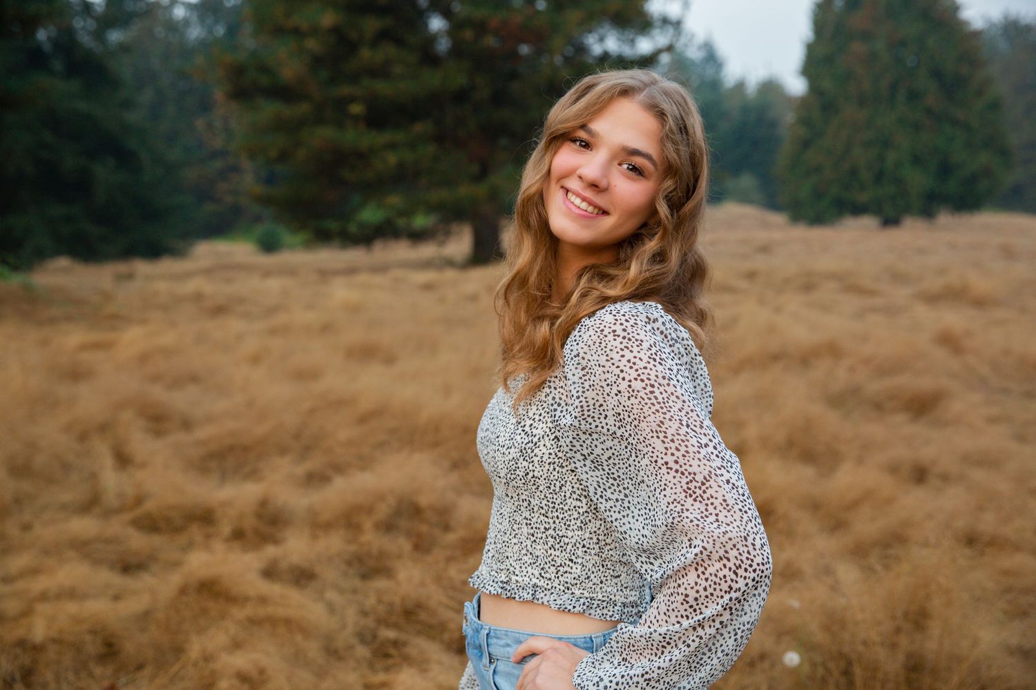 Senior portrait of a beautiful girl smiling in a field