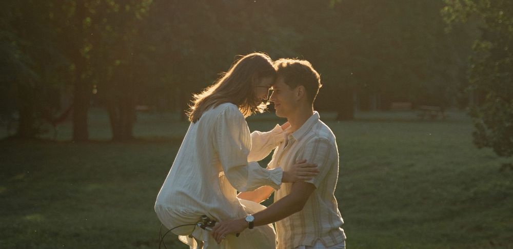 Romantic sunset scene of couple sharing intimate moment in park setting.