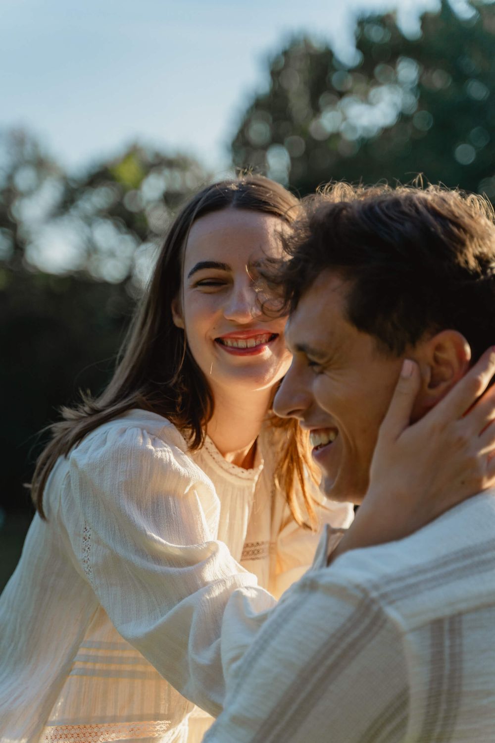 Sun-kissed portrait of couple laughing together in warm evening light.