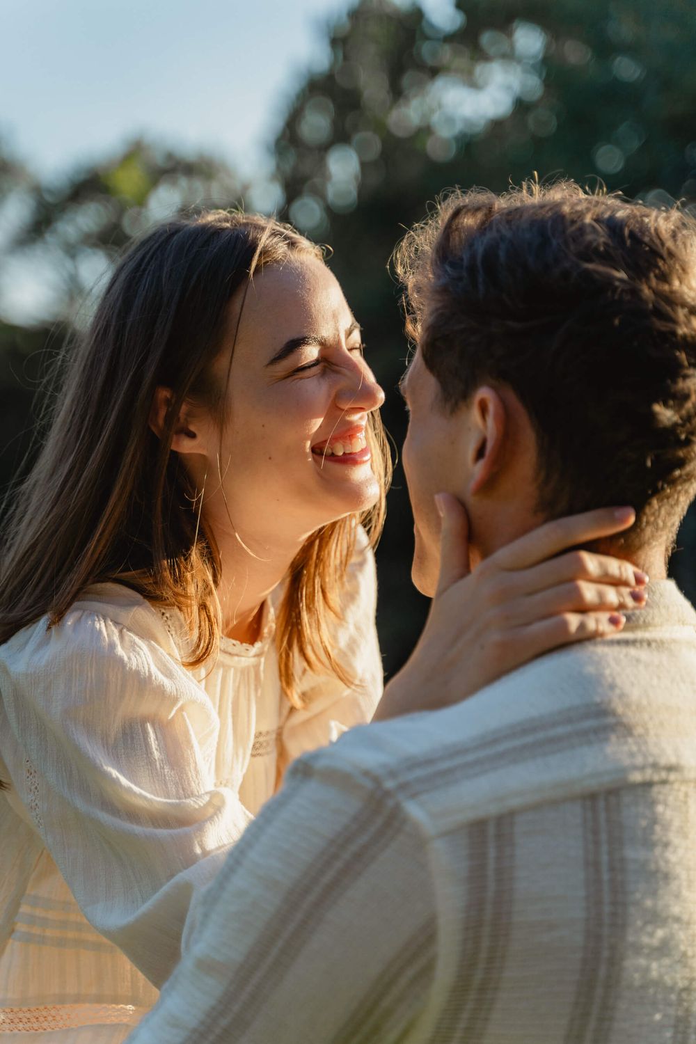 Intimate close-up of couple sharing joyful moment in golden hour lighting.