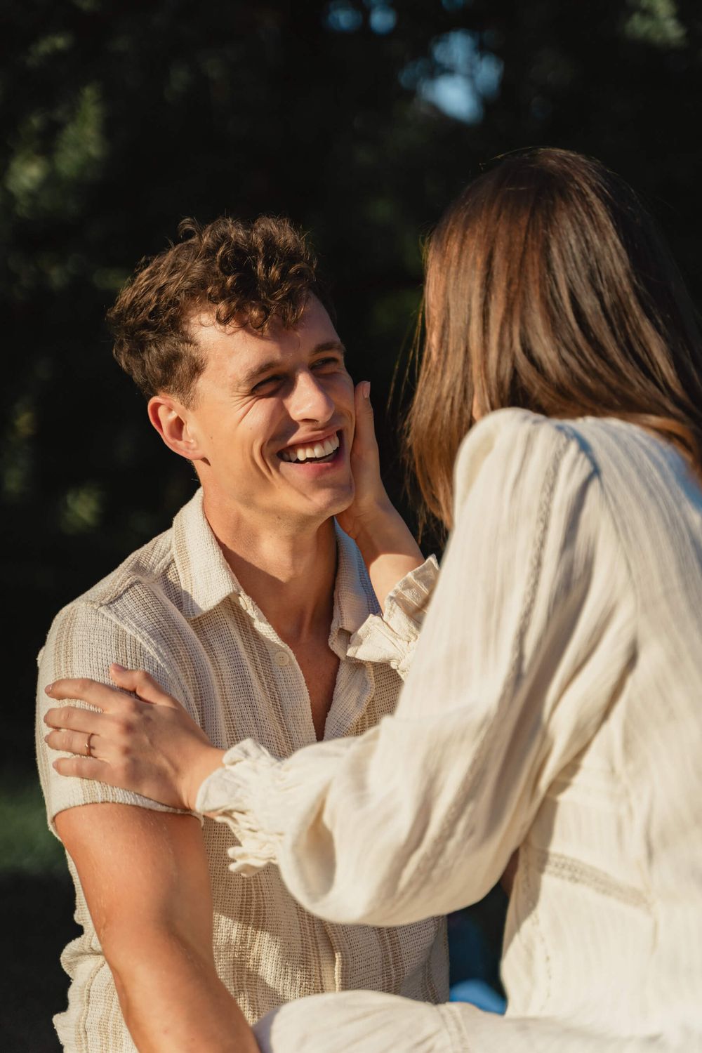 Natural candid moment of laughter and connection between couple in summer evening light.