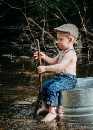 Child fishing with stick during creek stomp photography session