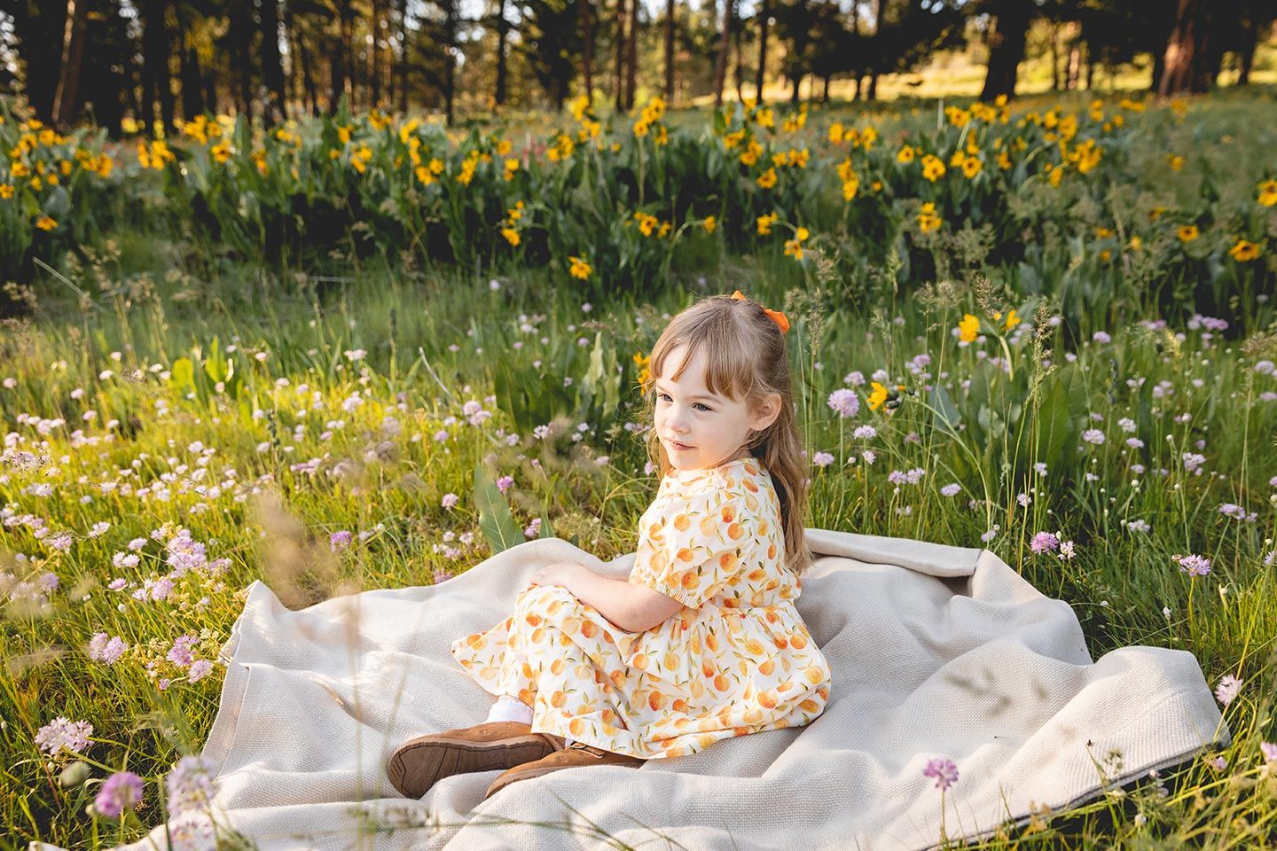 girl sitting on a blanket in the middle of mountain wildflowers