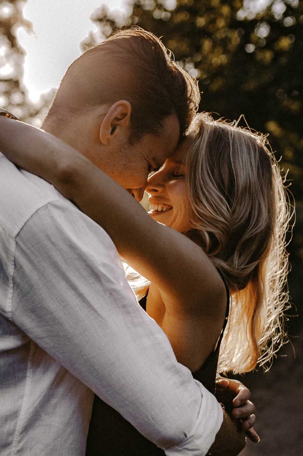 Romantic sunset embrace between couple captured in warm golden light.