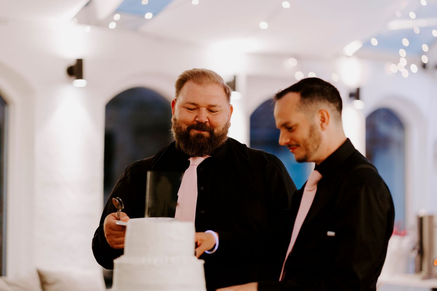 Two guests share a light moment while looking at a cake during the reception.