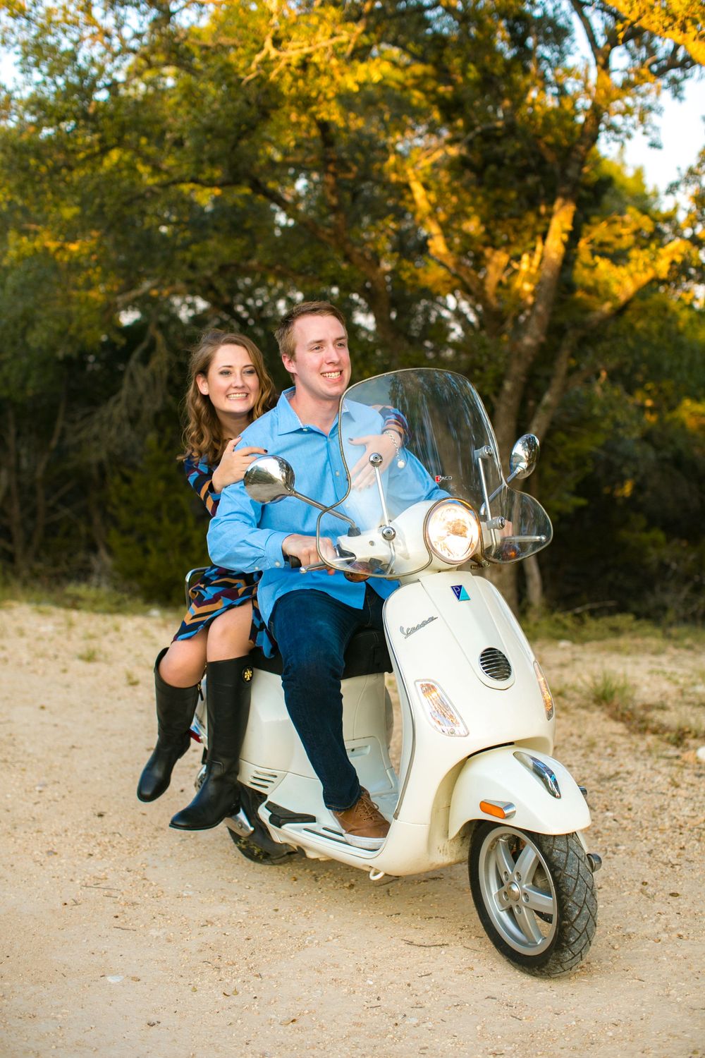 A stylish white Vespa scooter serves as a romantic prop during an autumn engagement photoshoot at sunset.