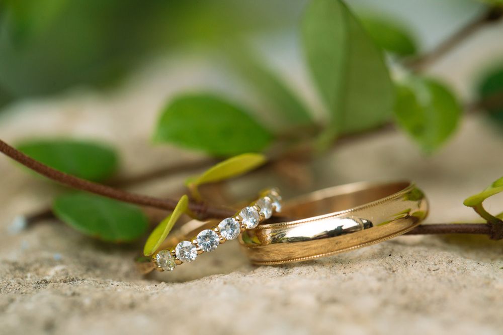 Close-up of gold wedding rings with diamonds on a stone surface