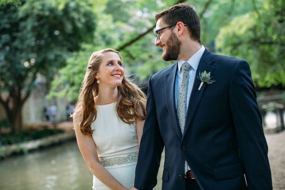 Candid wedding portraits of couple walking and laughing together in a leafy park setting.